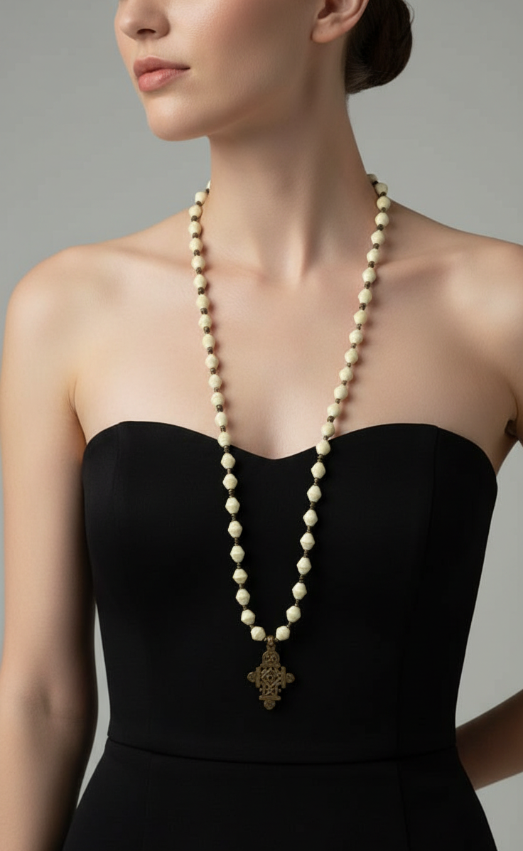Woman wearing a long pearl necklace with a black strapless top against a neutral background