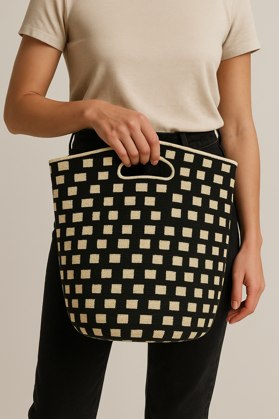 A person holding a black and beige checkered handbag.