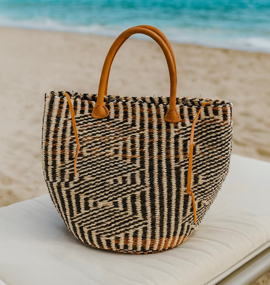 Woven bag with brown handles on a chair by the beach