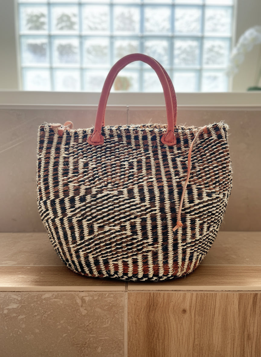 Woven bag with pink handles on a wooden surface