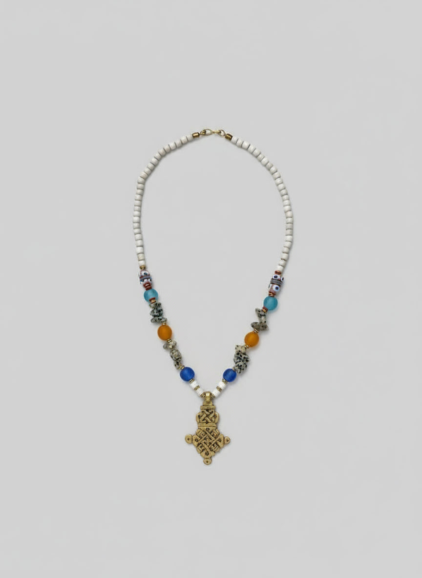 Necklace with beads and a decorative pendant on a light gray background